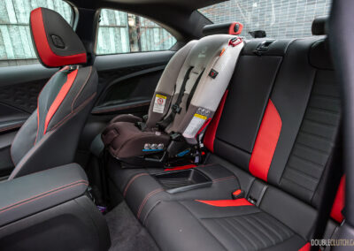 2025 BMW M240i xDrive interior rear-seat view with a child seat installed