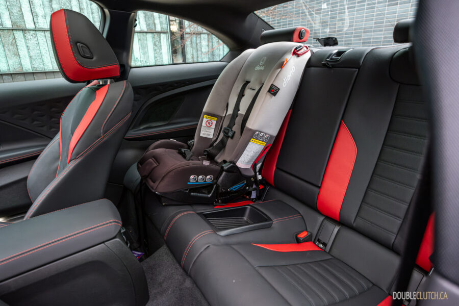 2025 BMW M240i xDrive interior rear-seat view with a child seat installed