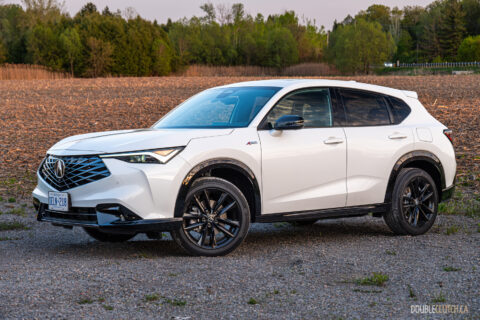 Front quarter view of a white 2025 Acura ADX parked on a dirt road, with trees and a field in the background