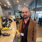 An exceptionally bald, strange man in an awful blazer holding a sweet banane in a Second Cup coffee shop at MTCC.