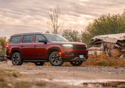 2025 Jeep Wagoneer Overland Edition in Velvet Red positioned menacingly next to a destroyed Winnebago